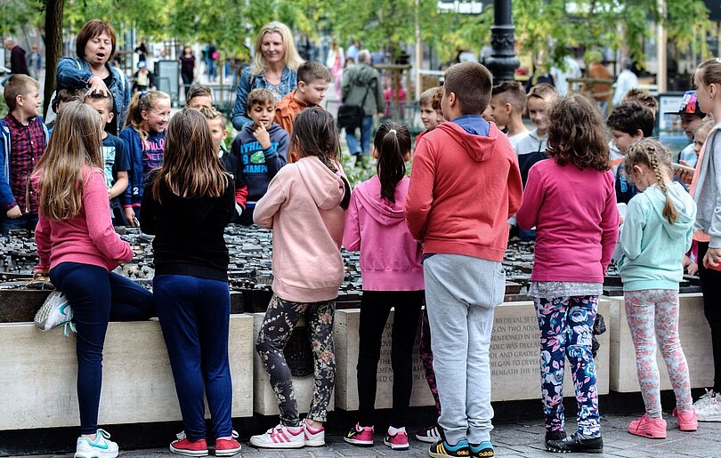 Eine Gruppe Schüler*innen und zwei Lehrerinnen stehen im Kreis und sind beim Reden