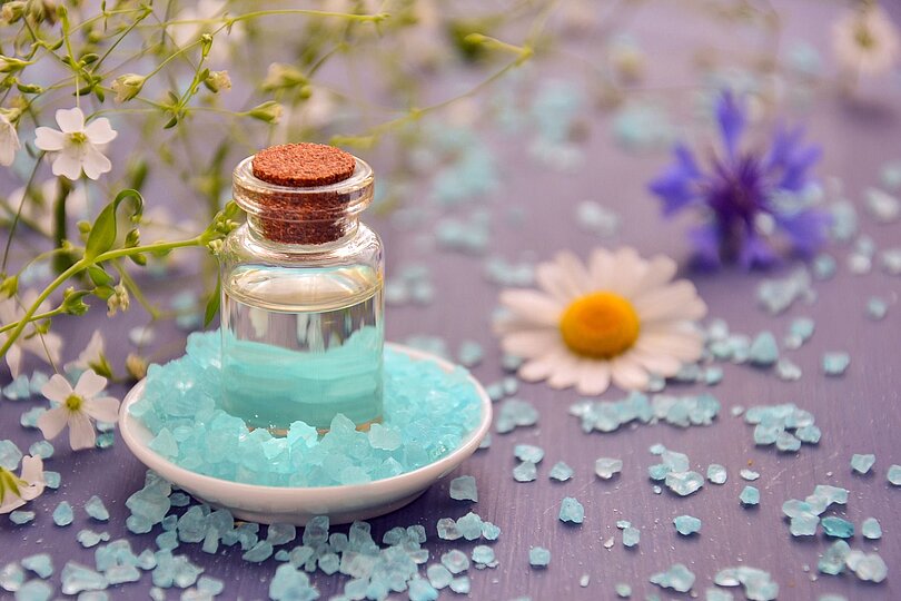 Salzkristallte, eine kleine Flasche mit Öl und Blumen