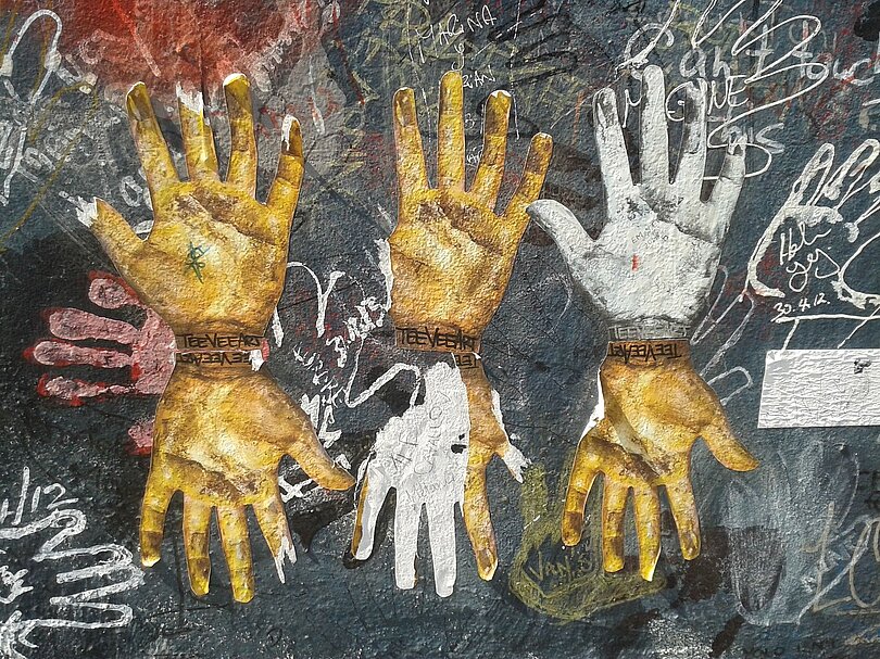 Kunstwerk durch Handabdrücke an der Berliner Mauer: Obere Reihe von links: zwei goldene und ein weißer Handabdruck schauen nach oben; untere Reihe von links: eine goldene, eine weiße und wieder eine goldene Hand schauen nach unten.