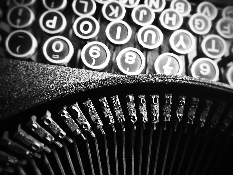 Ein Blick von oben auf eine alte Schreibmaschine. Man sieht die Tastatur und die Typenhebel. 