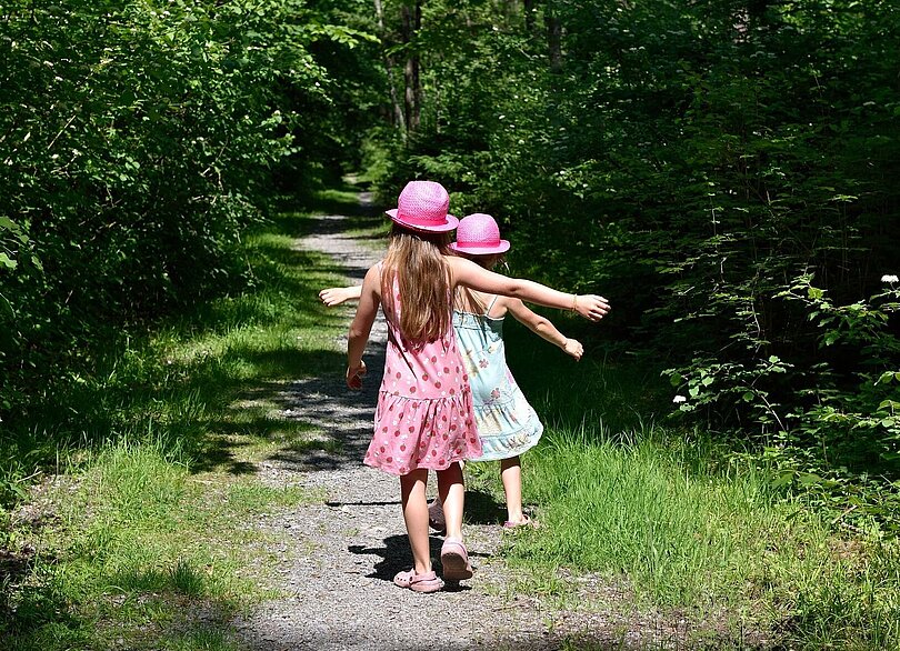 Zwei Mädchen tänzeln auf einem Waldweg