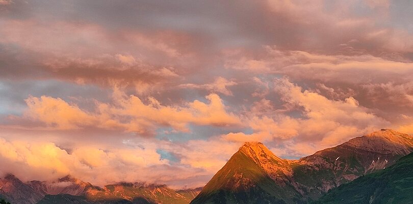 Sonnenuntergang in den Bergen mit Wolken, die rosa leuchten.